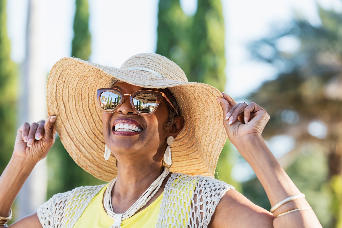 woman smiling while wearing a wide brim straw hat